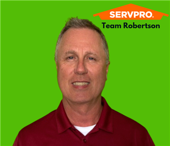 Smiling man on a green background with a SERVPRO logo