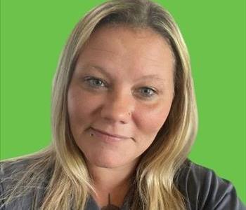 Woman in grey shirt in front of green background.