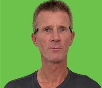 Man in black shirt in front of green background.